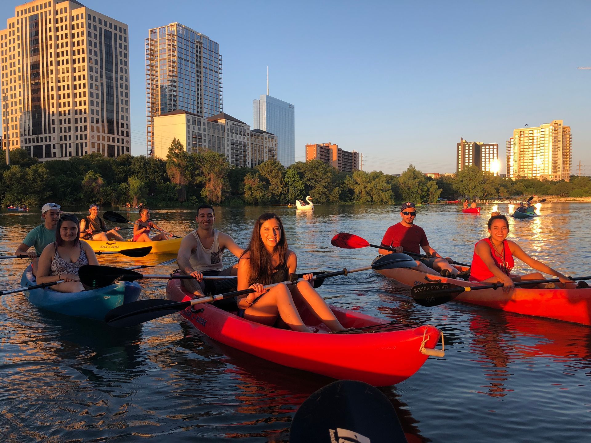 Boats and Bats tour group on sunset paddle with city skyline in background