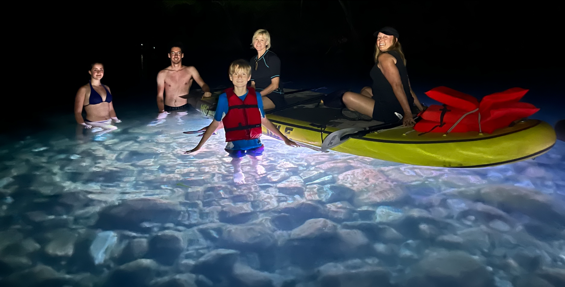Family on the glow paddle board tour with boats and bats
