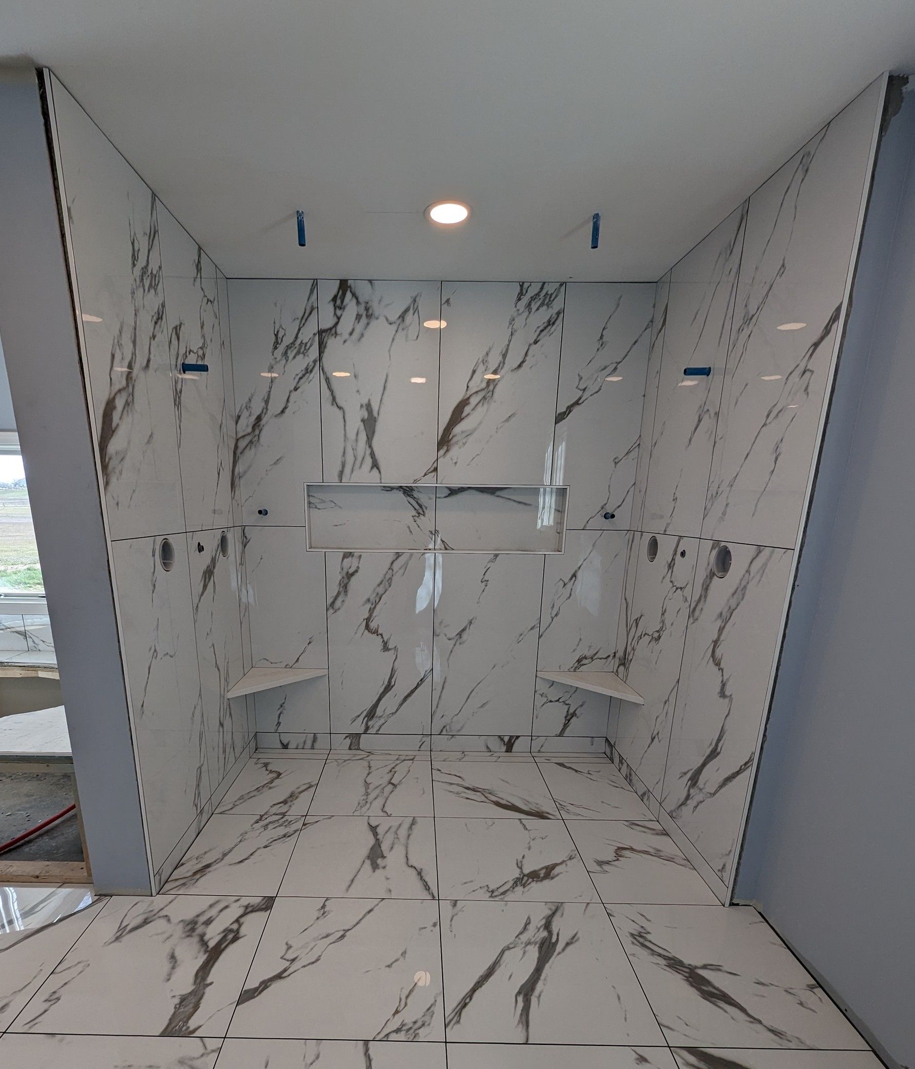 A bathroom with marble tiles and a walk in shower