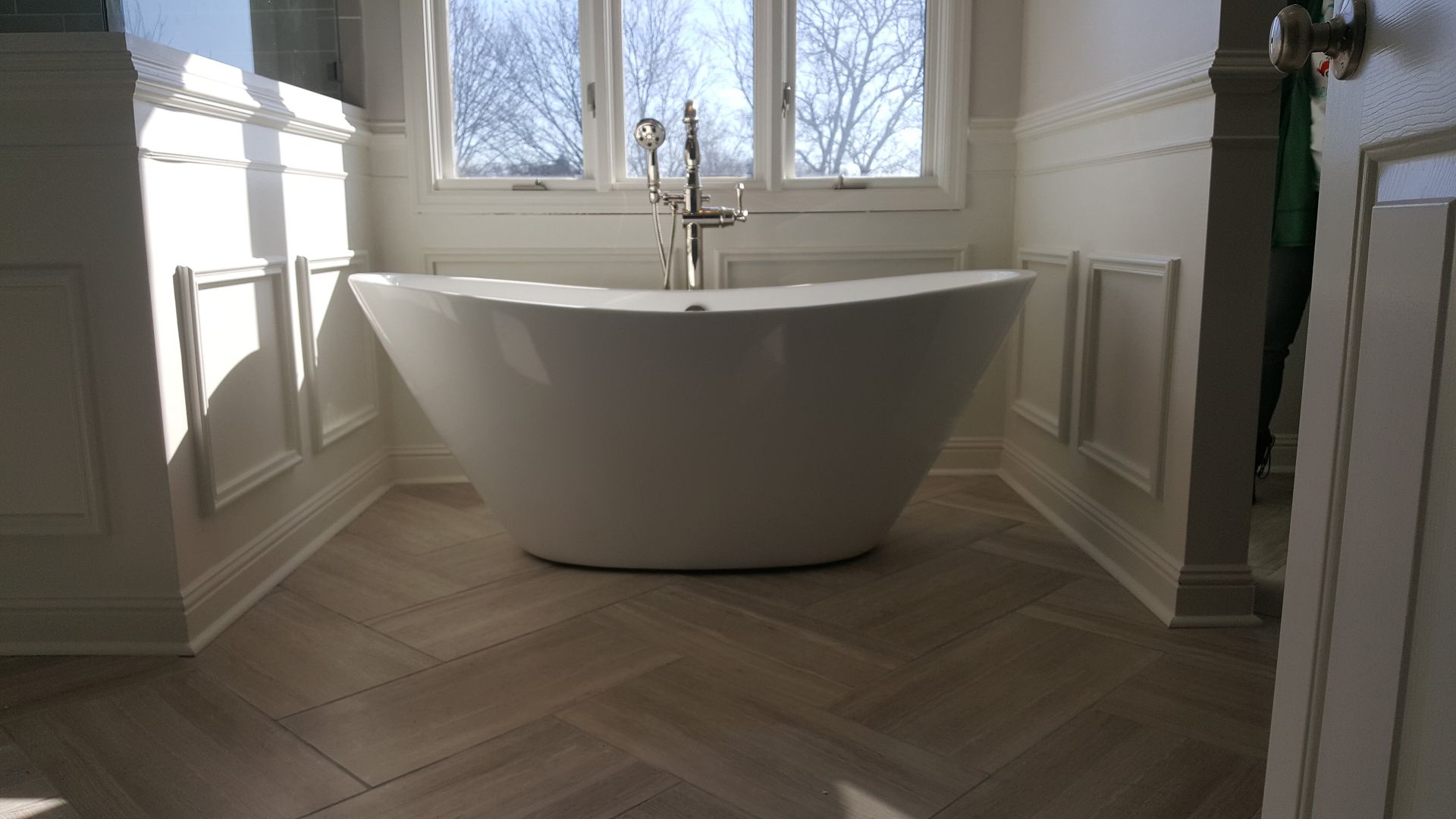 A white bathtub is sitting in a bathroom next to a window.