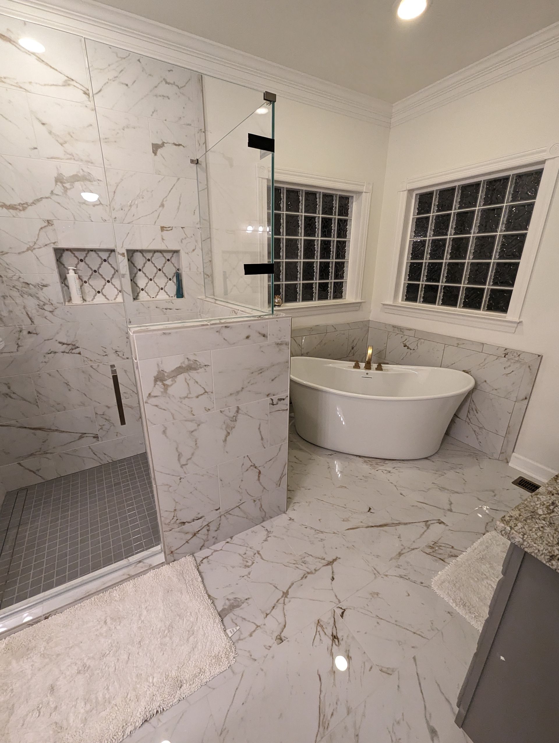 A bathroom with a tub , shower , and window large bathroom remodel including tile shower, floor and free standing tub.