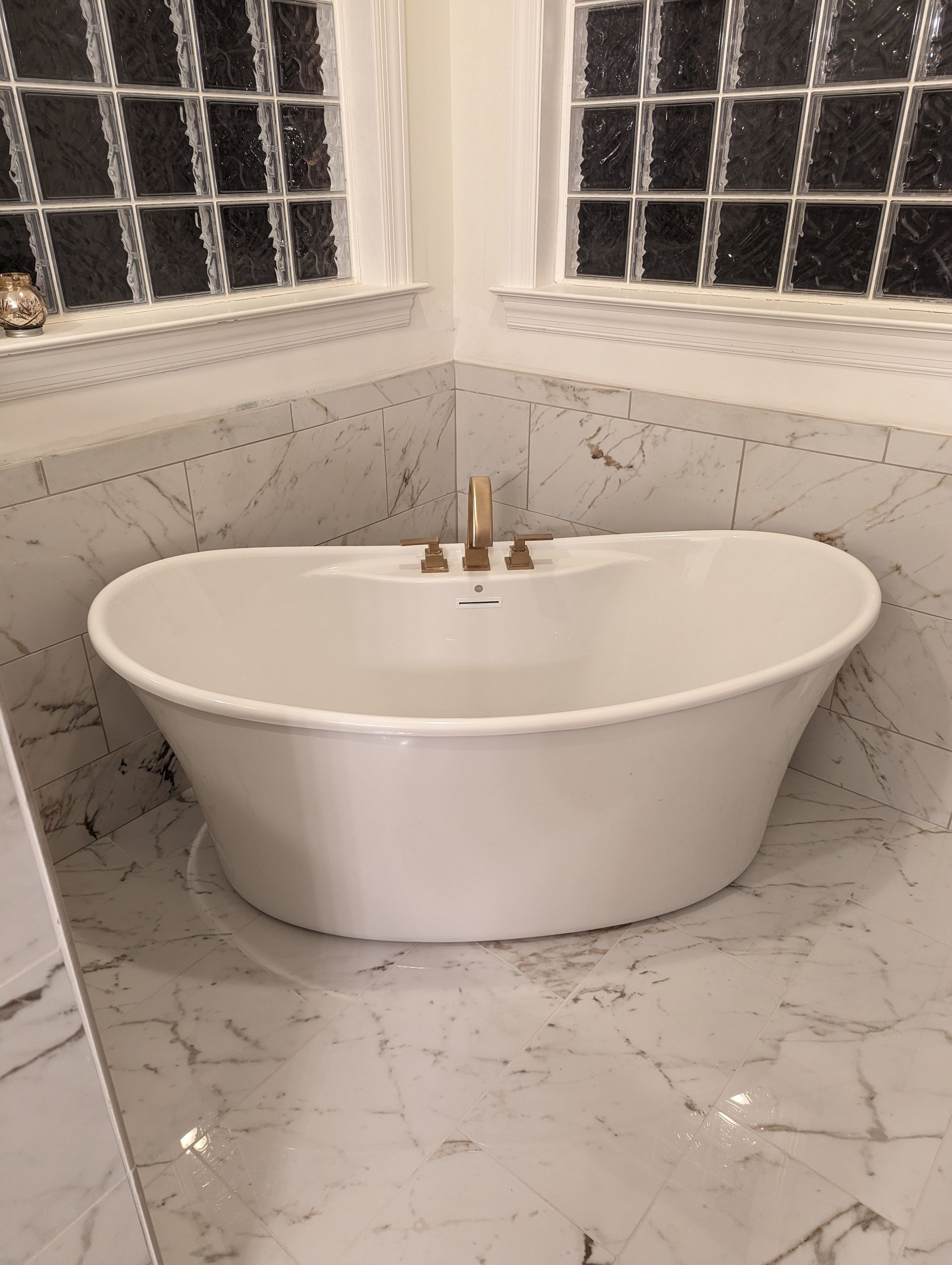 A white freestanding bathtub is sitting in the corner of a bathroom that was remodeled. 