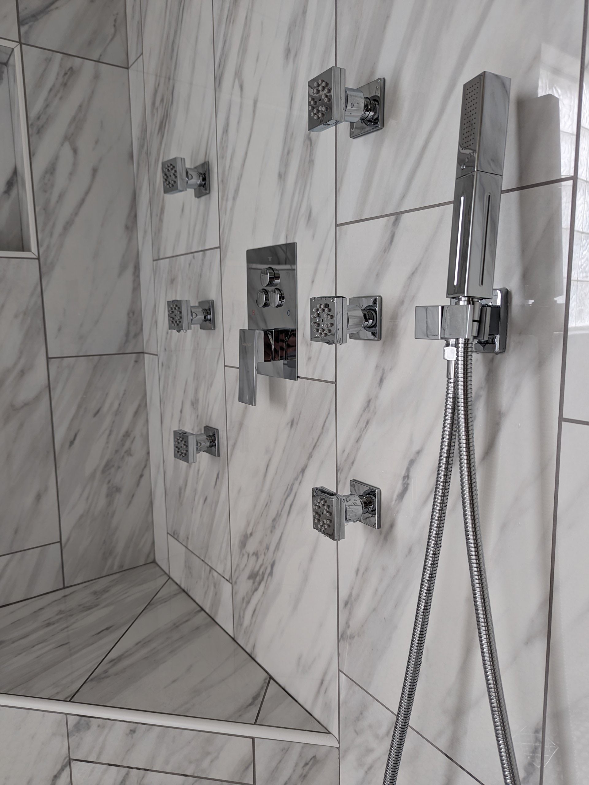 A bathroom with marble tiles and a shower head