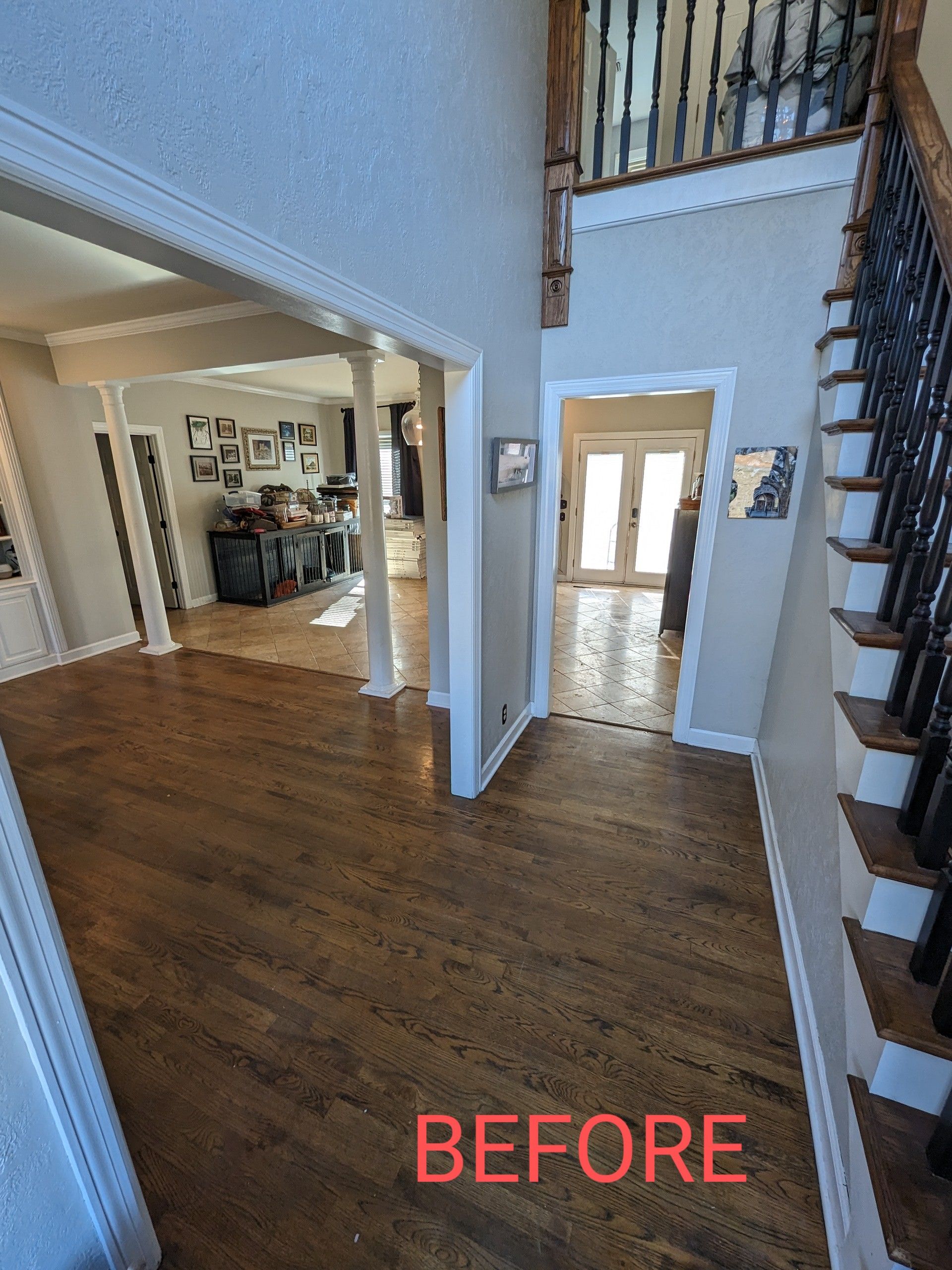 A before picture of a hallway with hardwood floors and stairs.