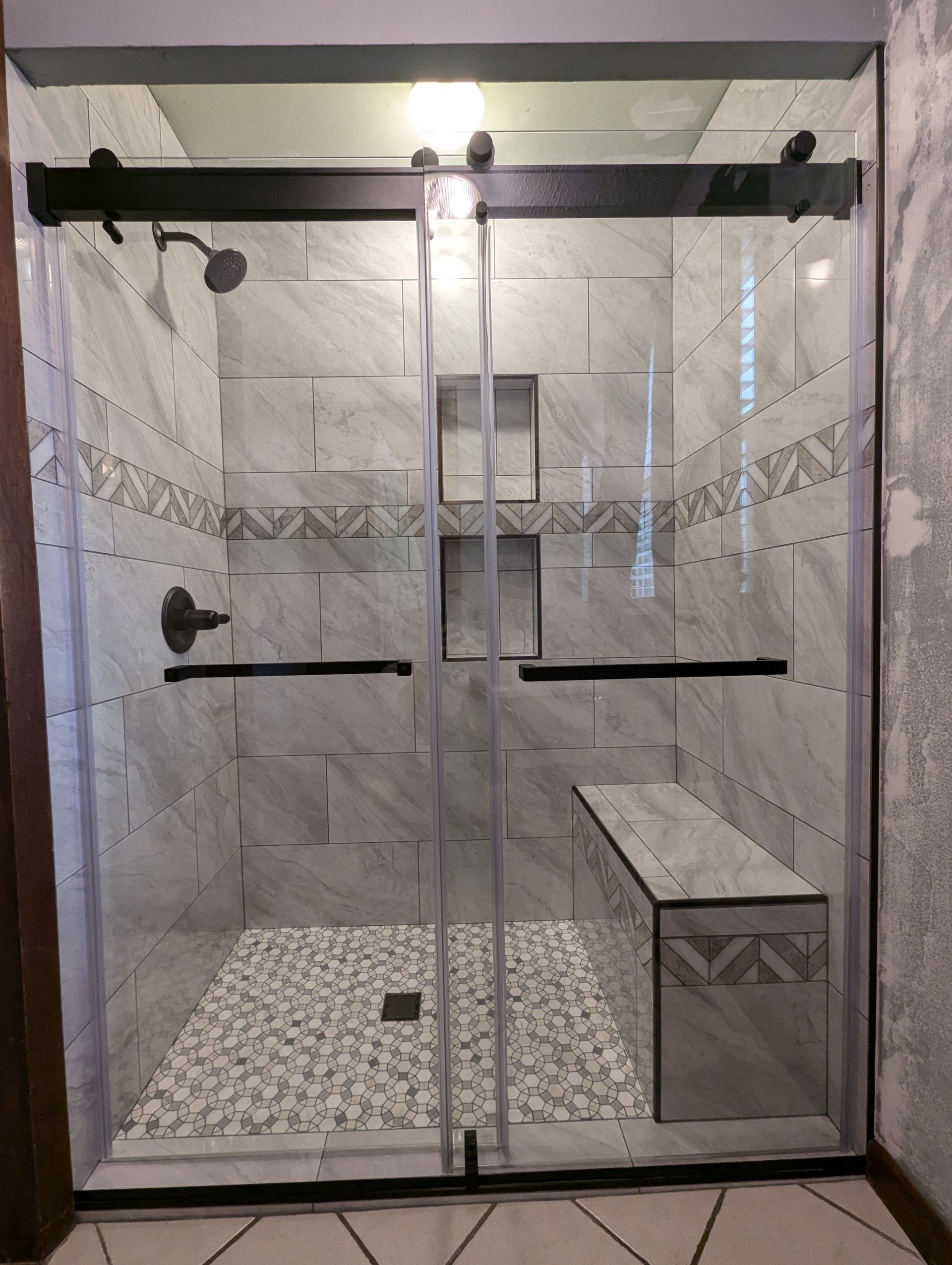 A shower with sliding glass doors and a bench