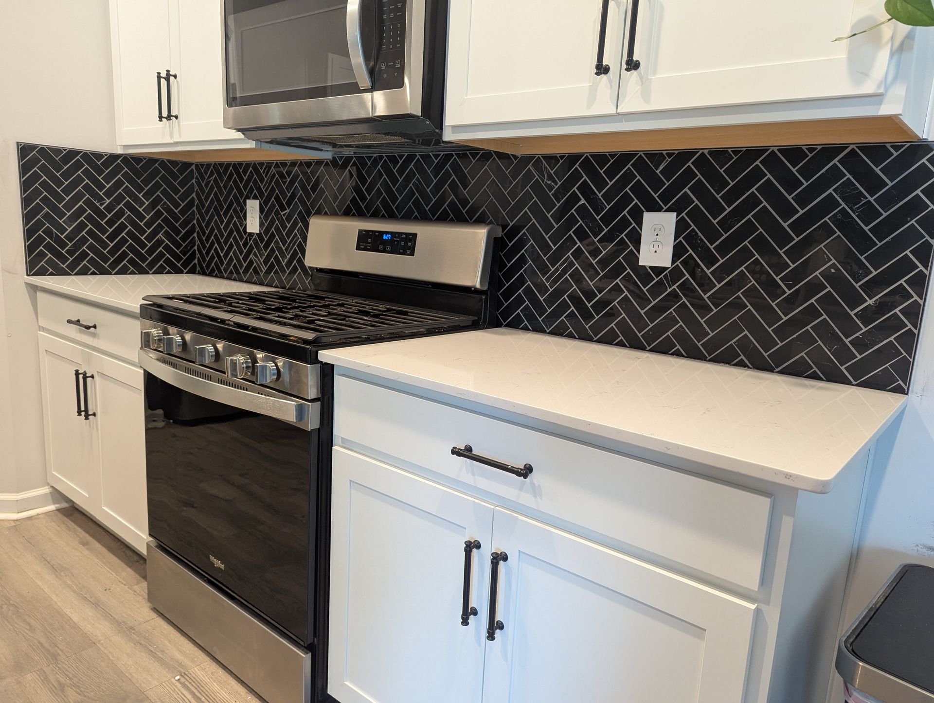 A kitchen with white cabinets , stainless steel appliances , a stove and a microwave.