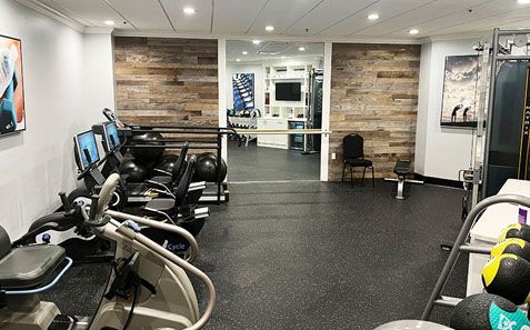Gym interior with exercise bikes, treadmills, weight machines, and a black rubber floor