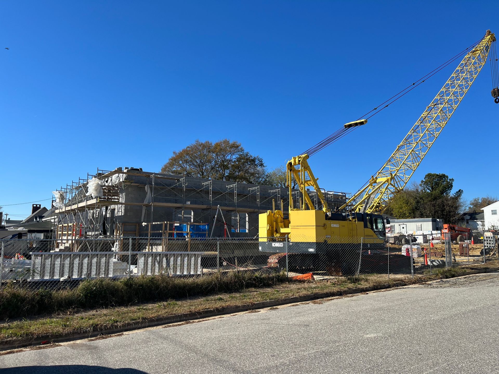 Construction site with crane and partially built brick structure under a clear blue sky