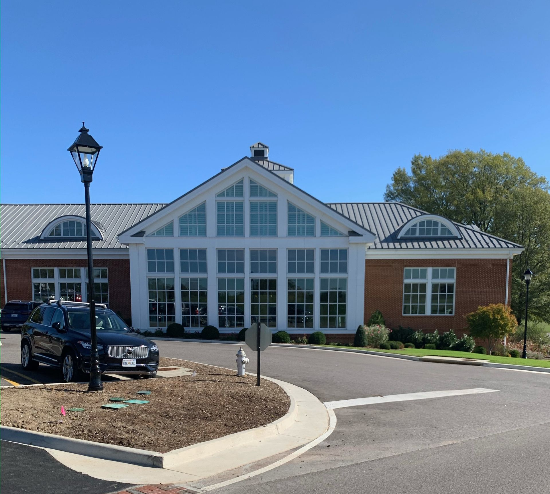 Brick building entrance with white-trimmed windows, parked car, and clear blue sky