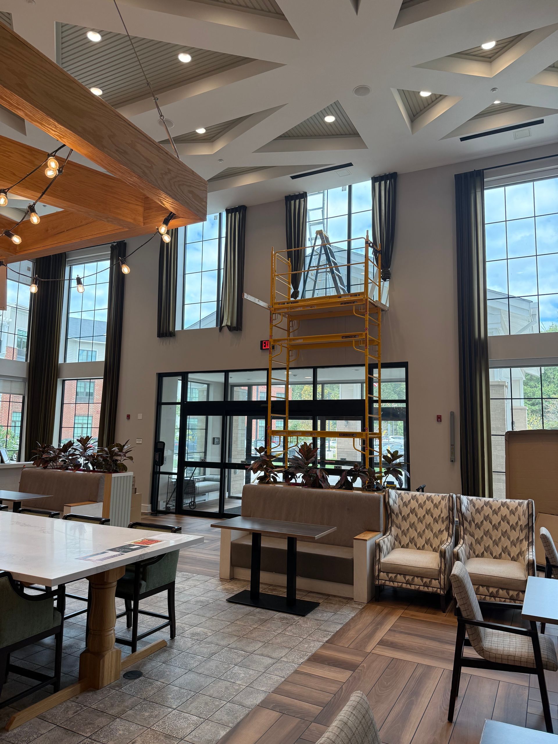Modern lobby with high ceilings, large windows, patterned tile, and lounge seating around a central bar area