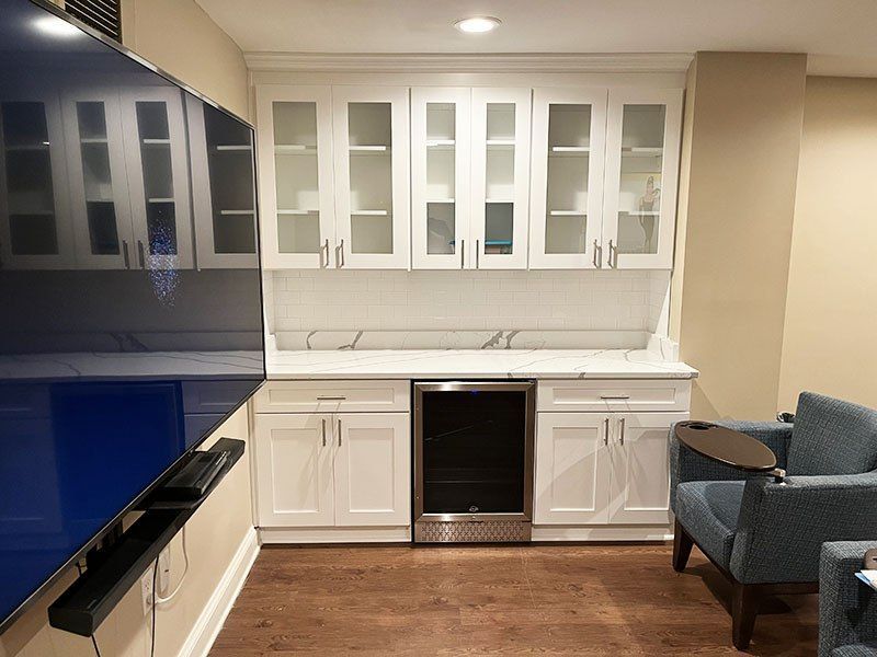 Modern kitchen with white cabinets, black countertops, and a blue upholstered chair by the island.