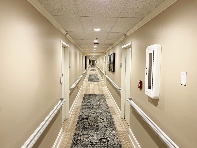 Long hotel hallway with beige walls, carpet runner, and doors lining both sides