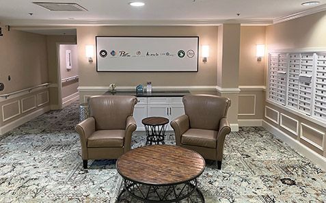 Quiet hotel lobby with two beige chairs, round table, and decorative wall art under soft lighting