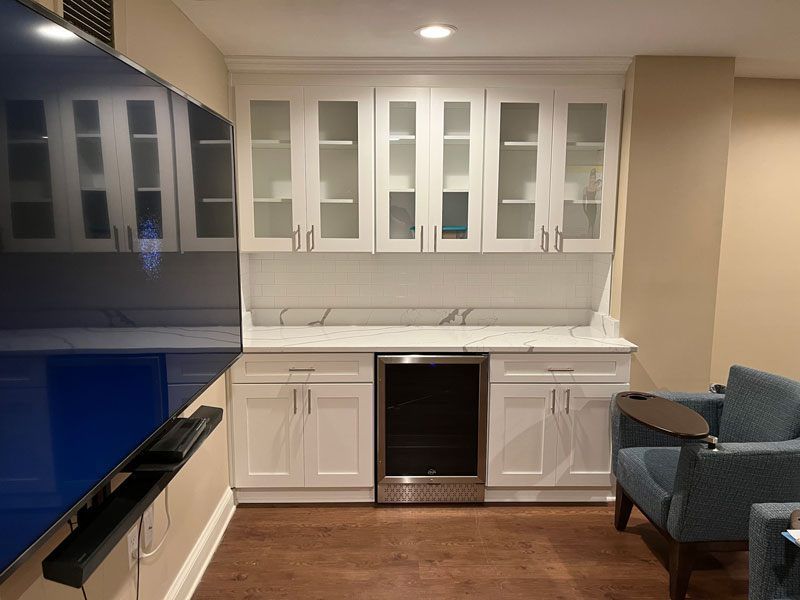 Modern kitchen with white cabinets, black appliances, and a small seating area by the window