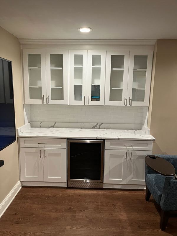 White built-in cabinet with glass doors and black mini fridge in a recessed room area
