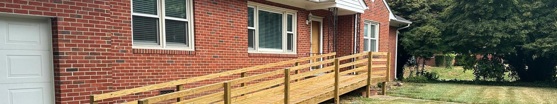 Brick house exterior with white-trimmed windows and a wooden fence in front