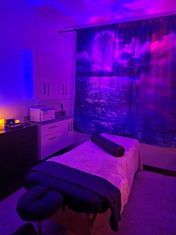 Blue-lit room with a person reclining in bed and a glowing candle centerpiece in the background