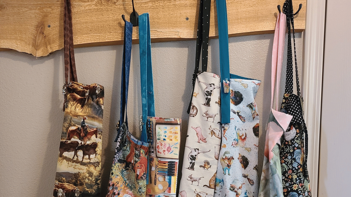 Assorted colorful aprons hanging on hooks against a wall.