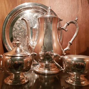 Polished silver tea set with tray and two cups on a wooden surface