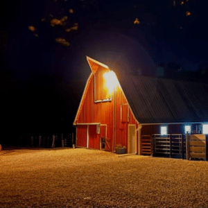 red barn with lights on inside and out in the darkness
