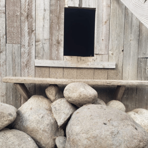 A weathered wooden wall with a dark, rectangular opening.