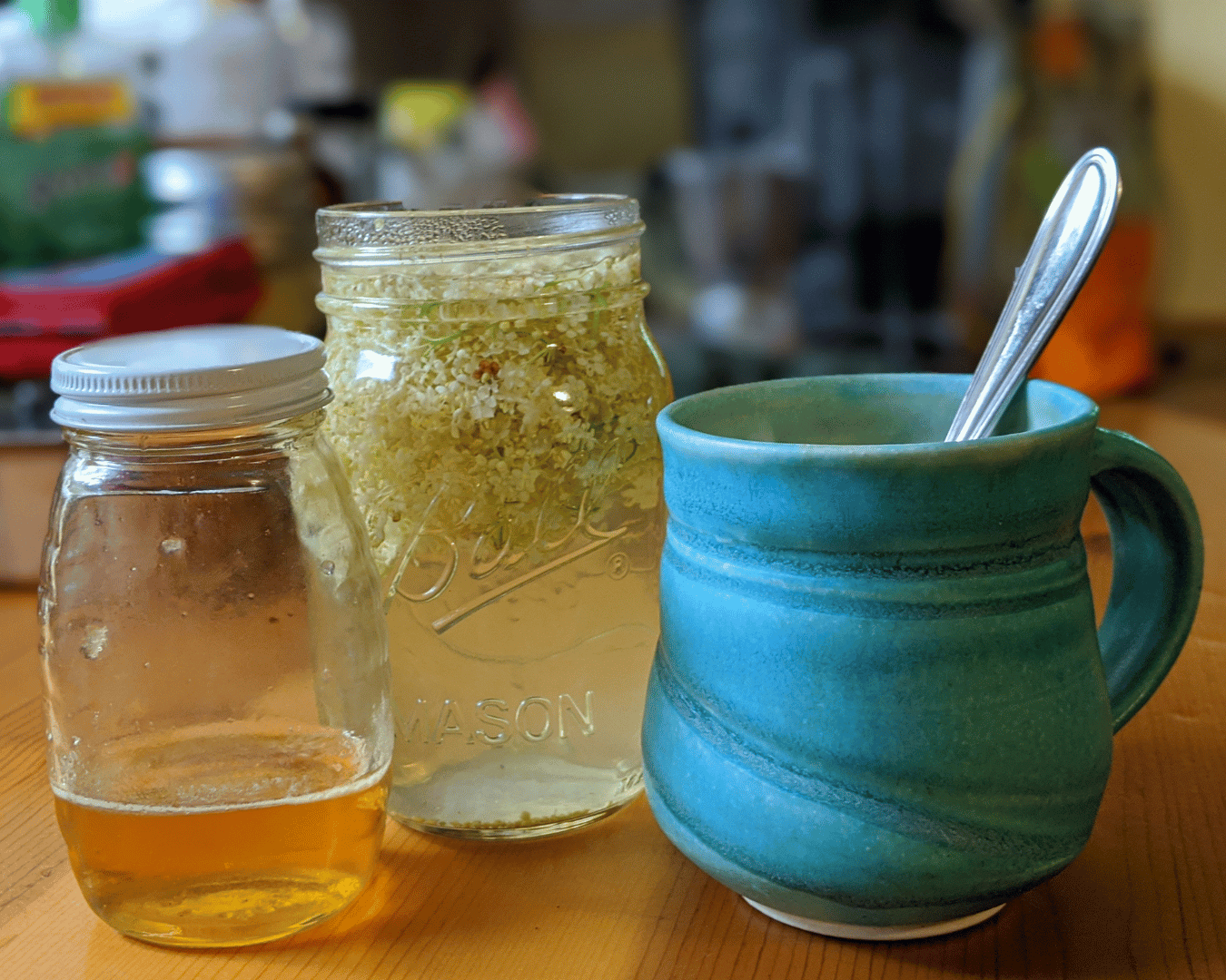 jar of honey, steeping elderflowers, blue mug with a spoon inside