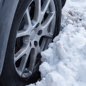 Car tire stuck in deep snow. Silver wheel and black tire.