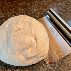 a ball of dough with a roots and harvest dough scraper
