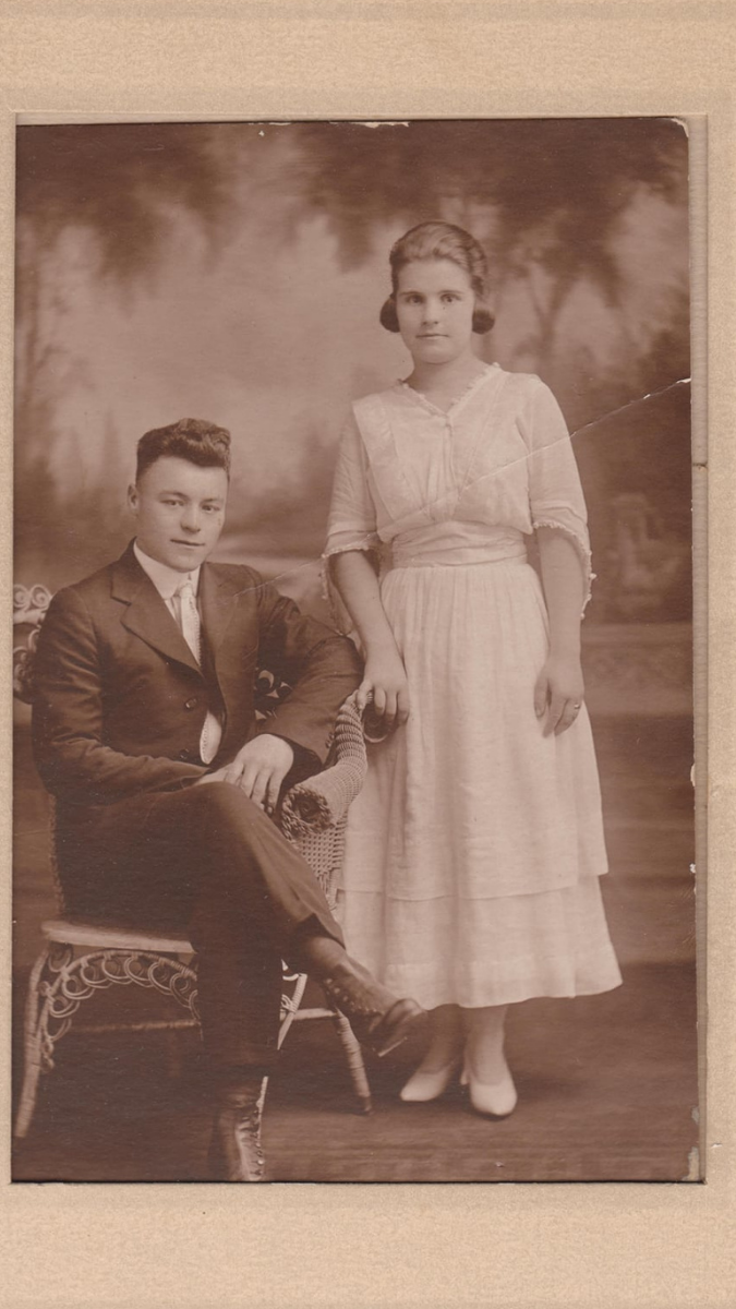 A formal portrait of a seated man and standing woman in sepia tones.