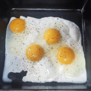 Fried eggs in a pan with pepper on top