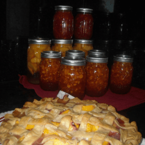 A pie sits on a table in front of home-canned jars of peaches