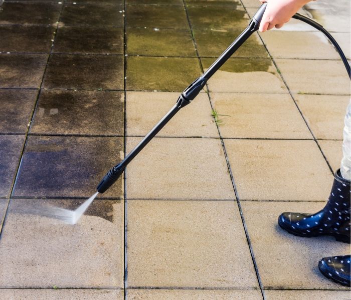 A person is peeling off wallpaper from a wall with a spatula.