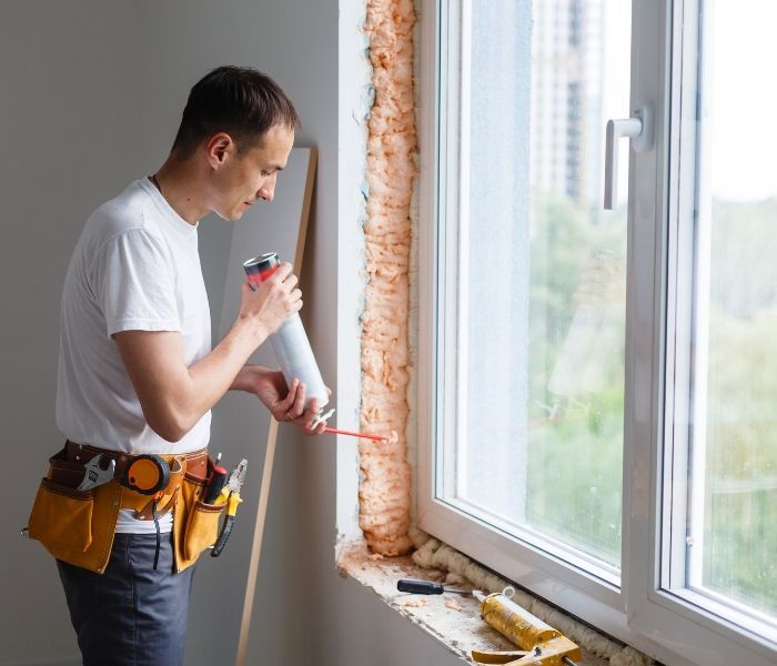 A person is removing wallpaper from a wall with a spatula.