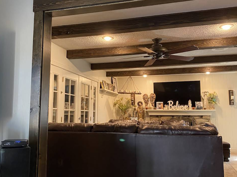 A living room with a couch , fireplace , television and ceiling fan.