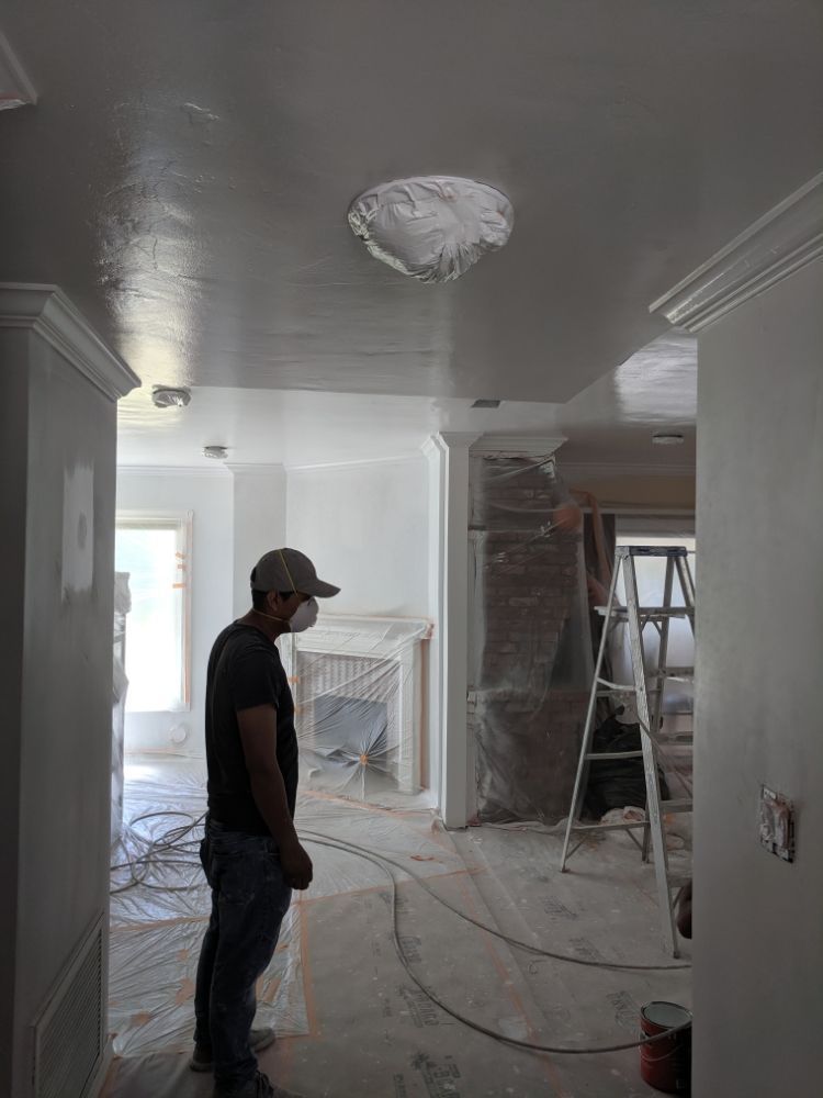 A man wearing a mask is standing in a room with a ladder.