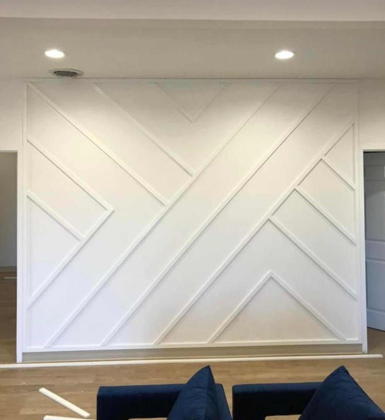 A living room with a white wall with a geometric pattern on it.