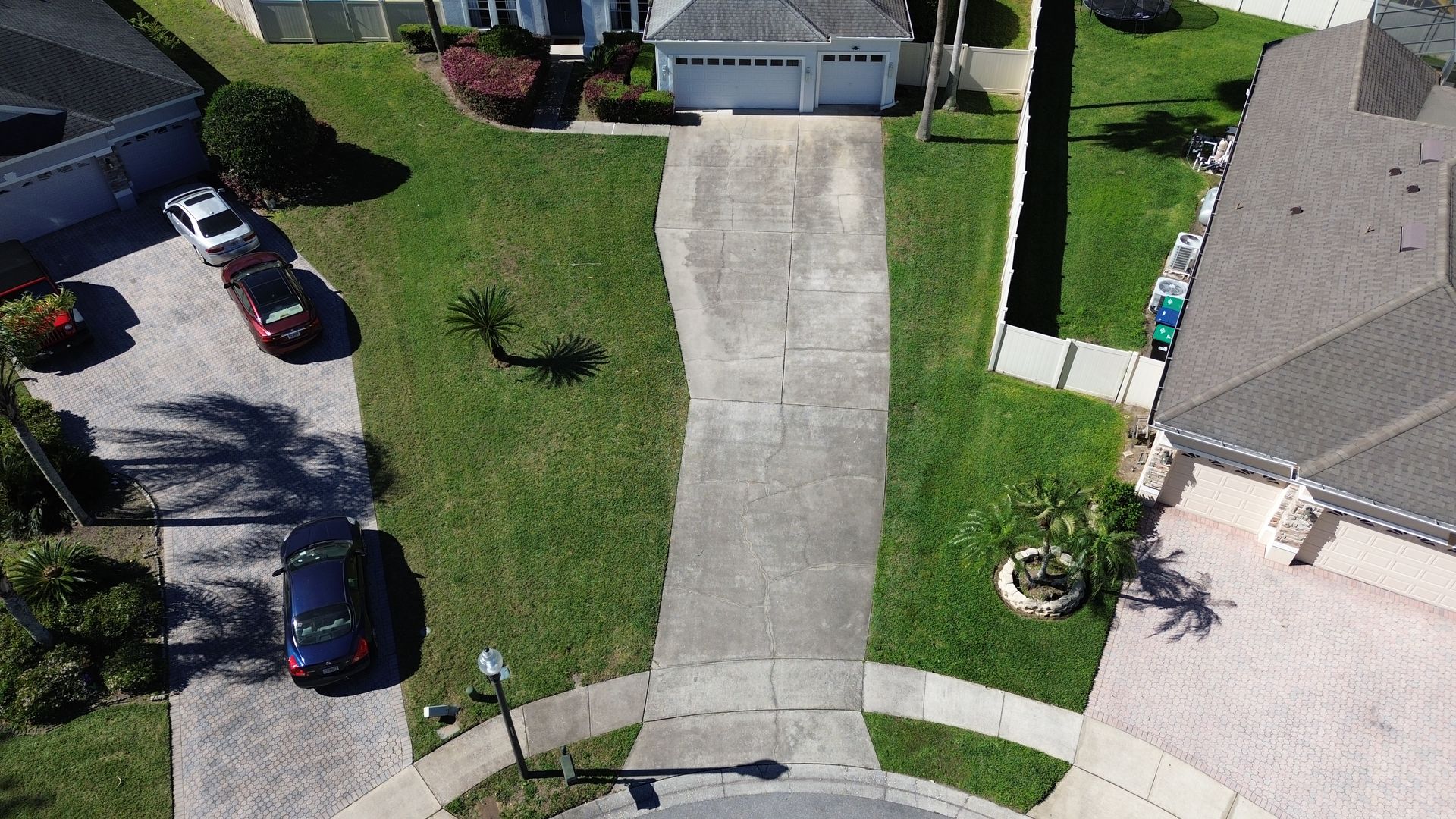 An aerial view of a residential neighborhood with a driveway leading to a house.