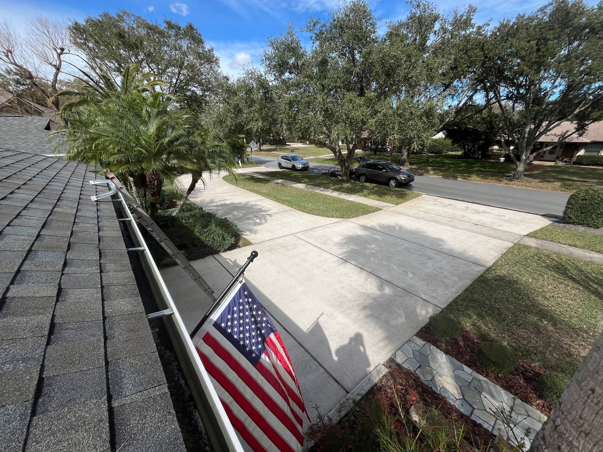 An american flag is hanging from a gutter on the side of a house.