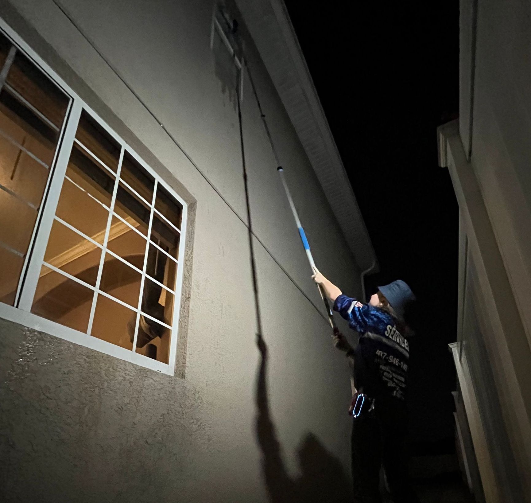 A man is cleaning the outside of a building at night