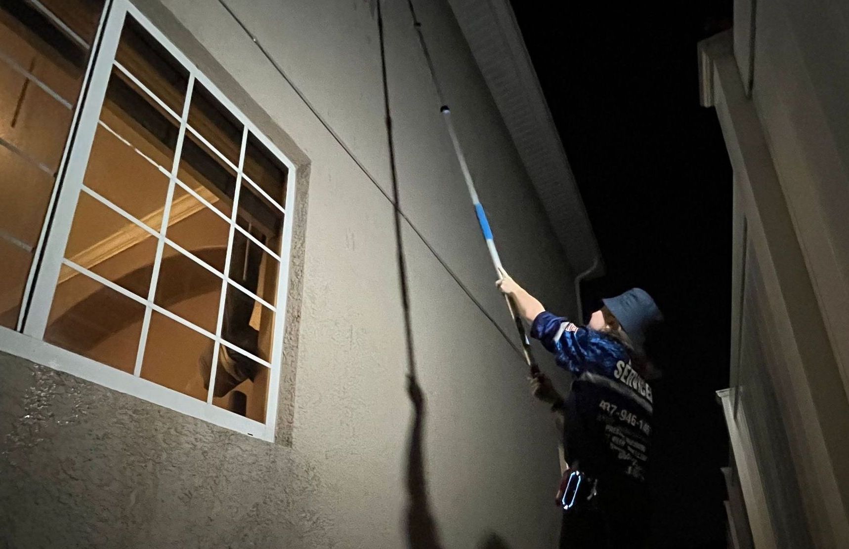A man is cleaning a window with a long pole.