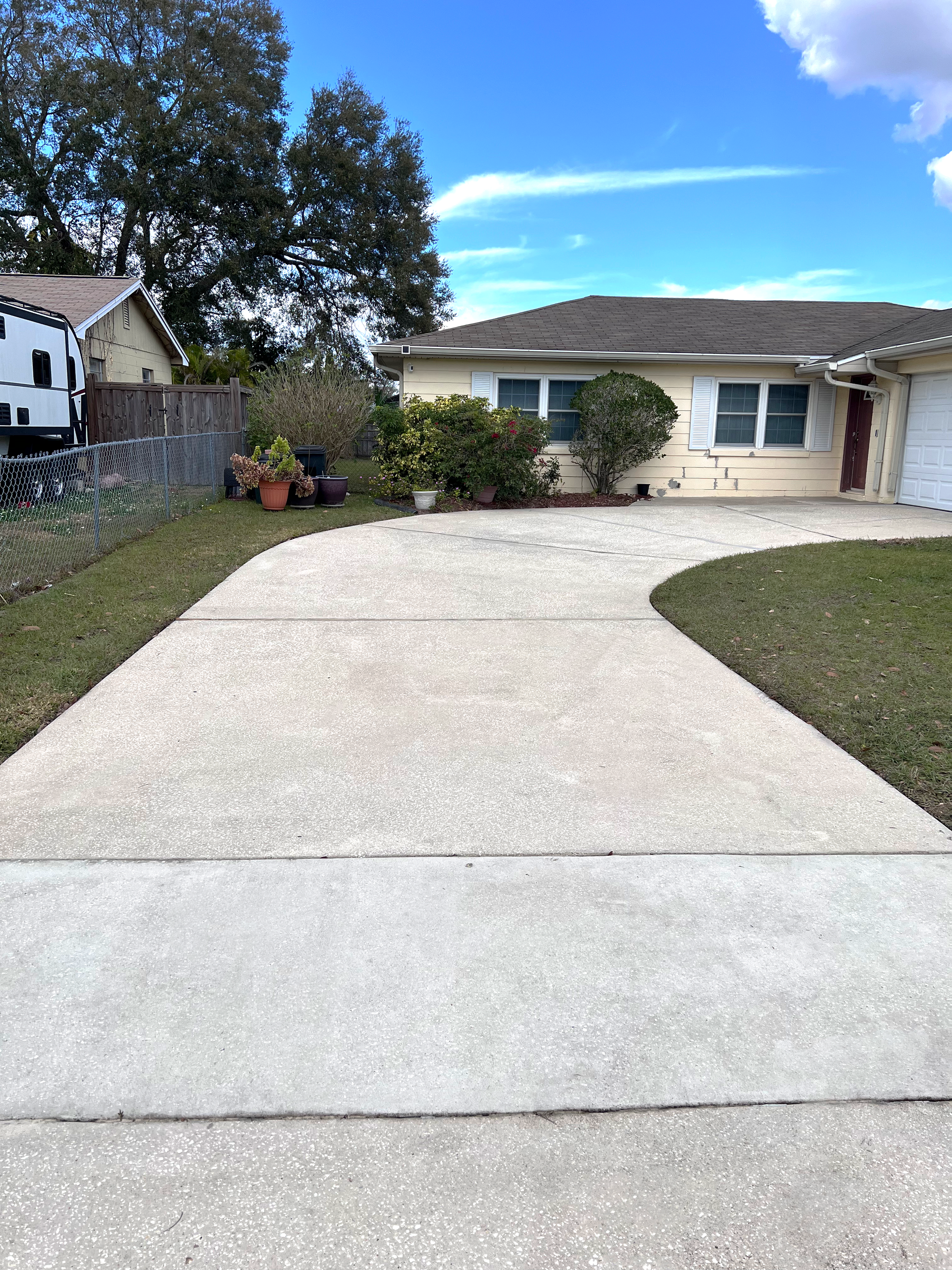 A concrete driveway leading to a house with a trailer parked in front of it.