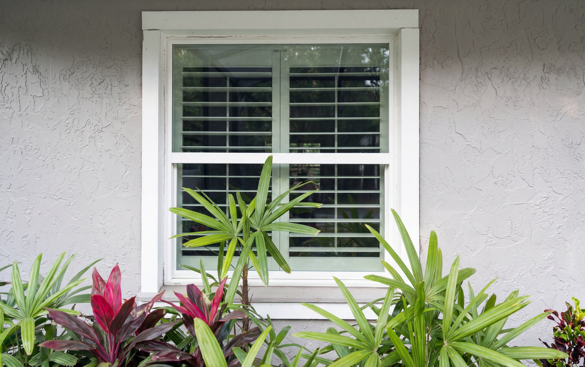A large window with shutters on it is on the side of a house.