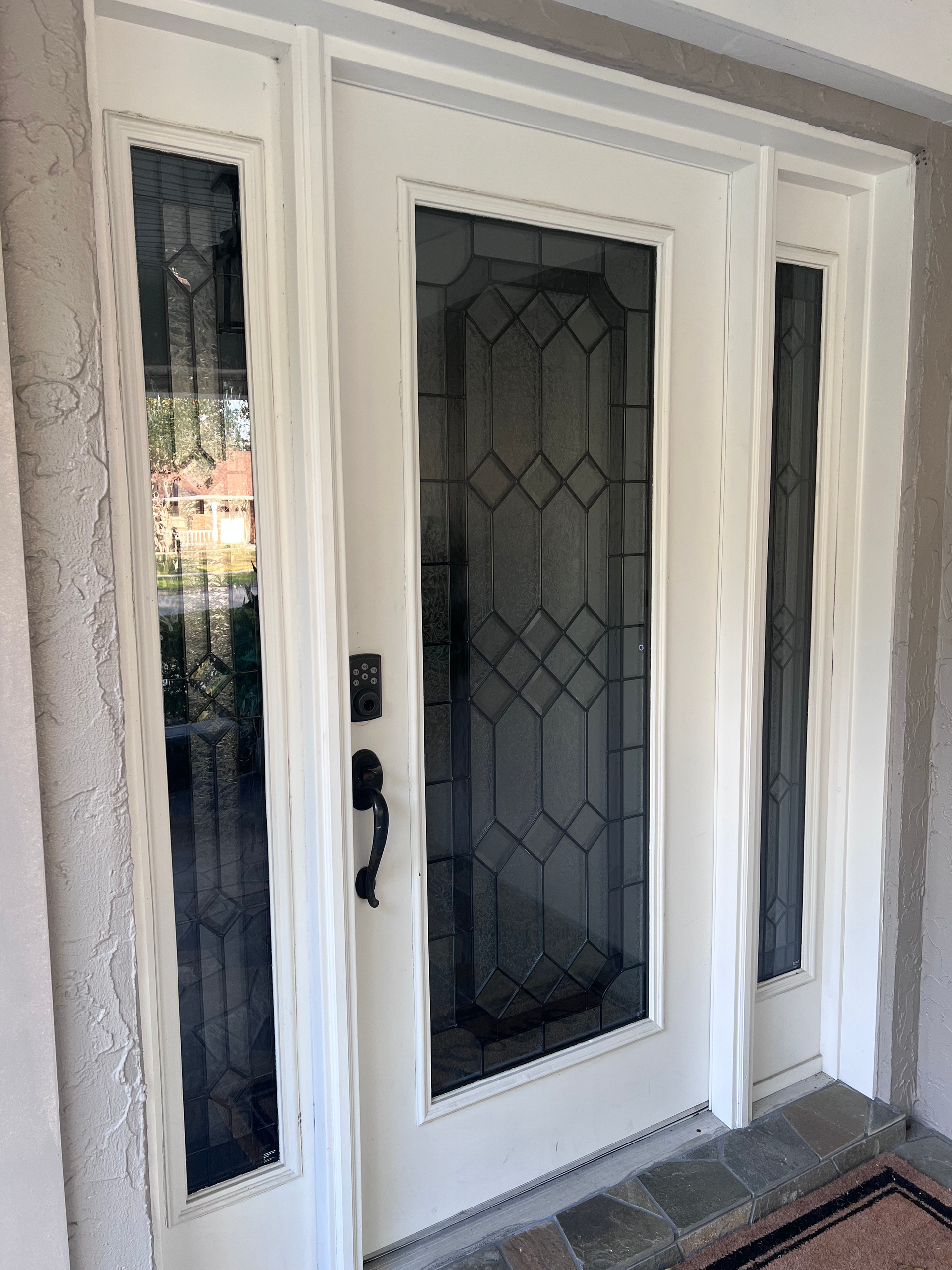 A white front door with stained glass windows and a black handle.
