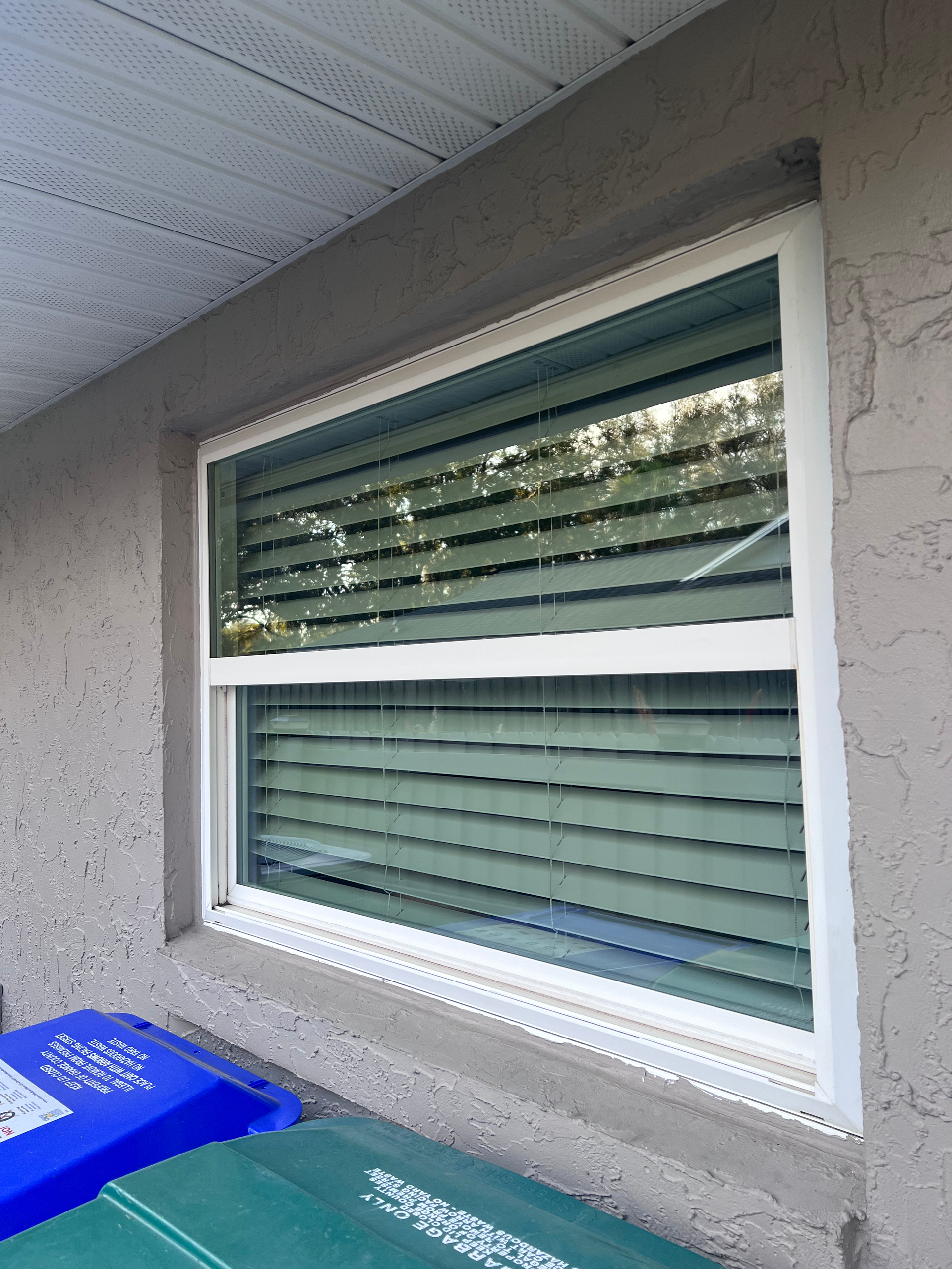 A window with blinds on it is on the side of a building.