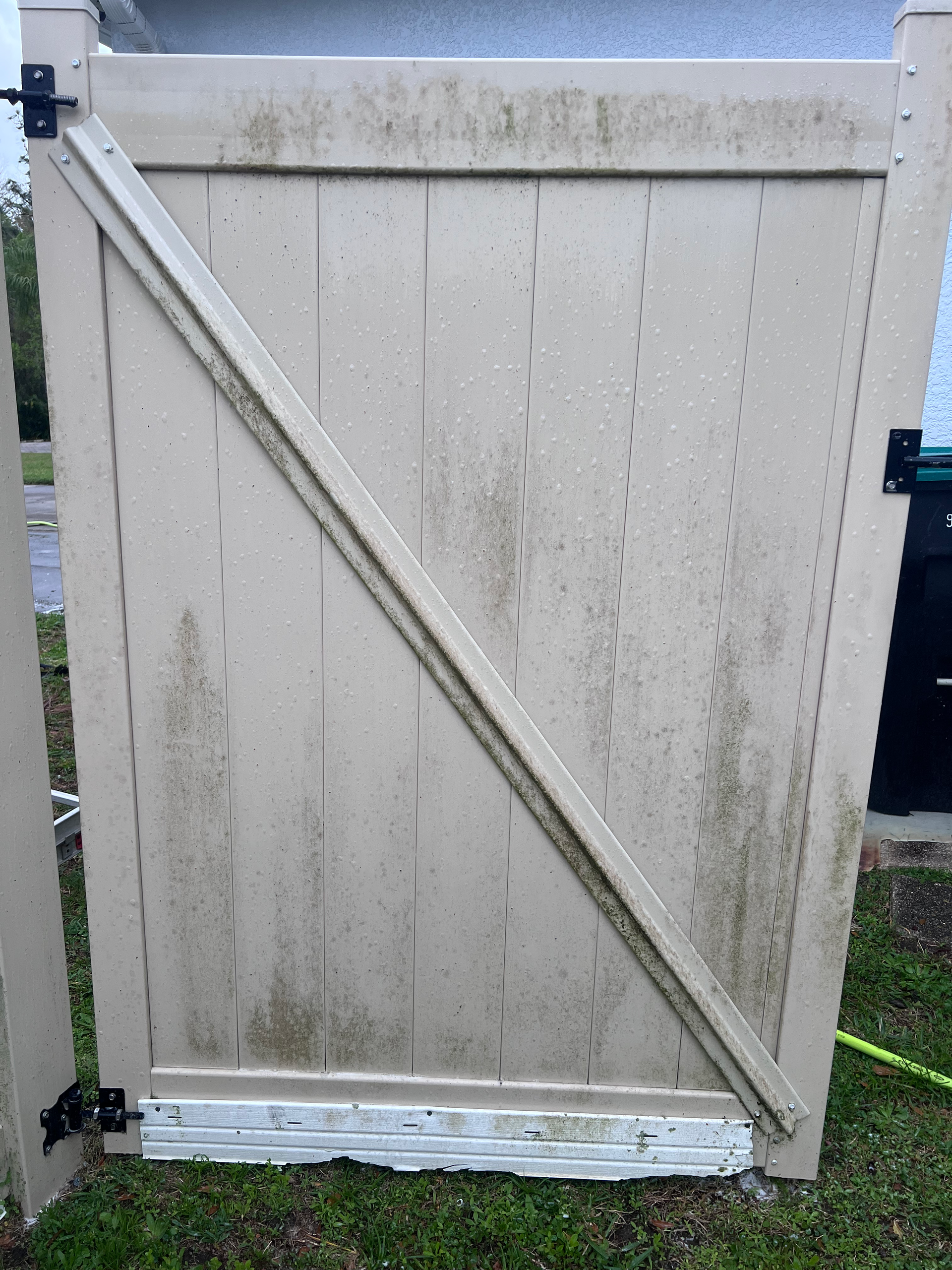 A dirty white gate is sitting on top of a lush green field.