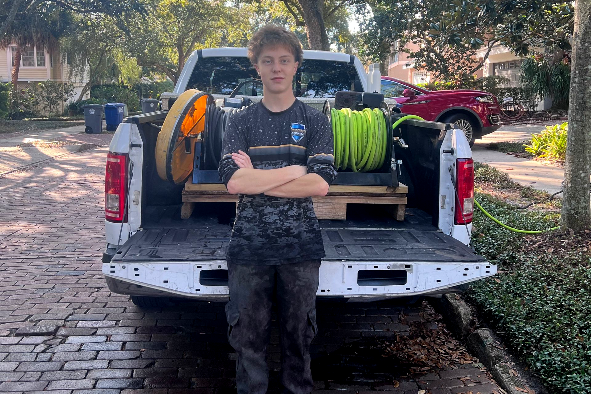 A person stands in front of a pickup truck with equipment.