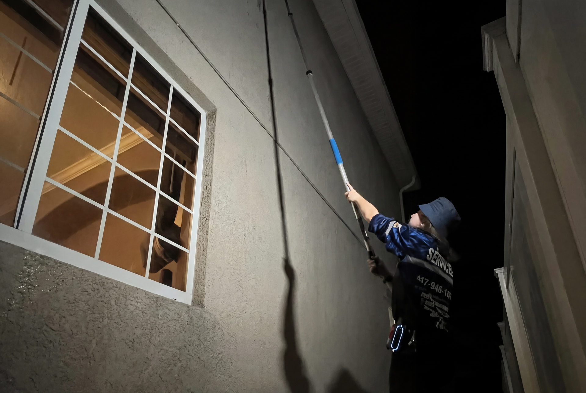 A man is cleaning the outside of a building at night