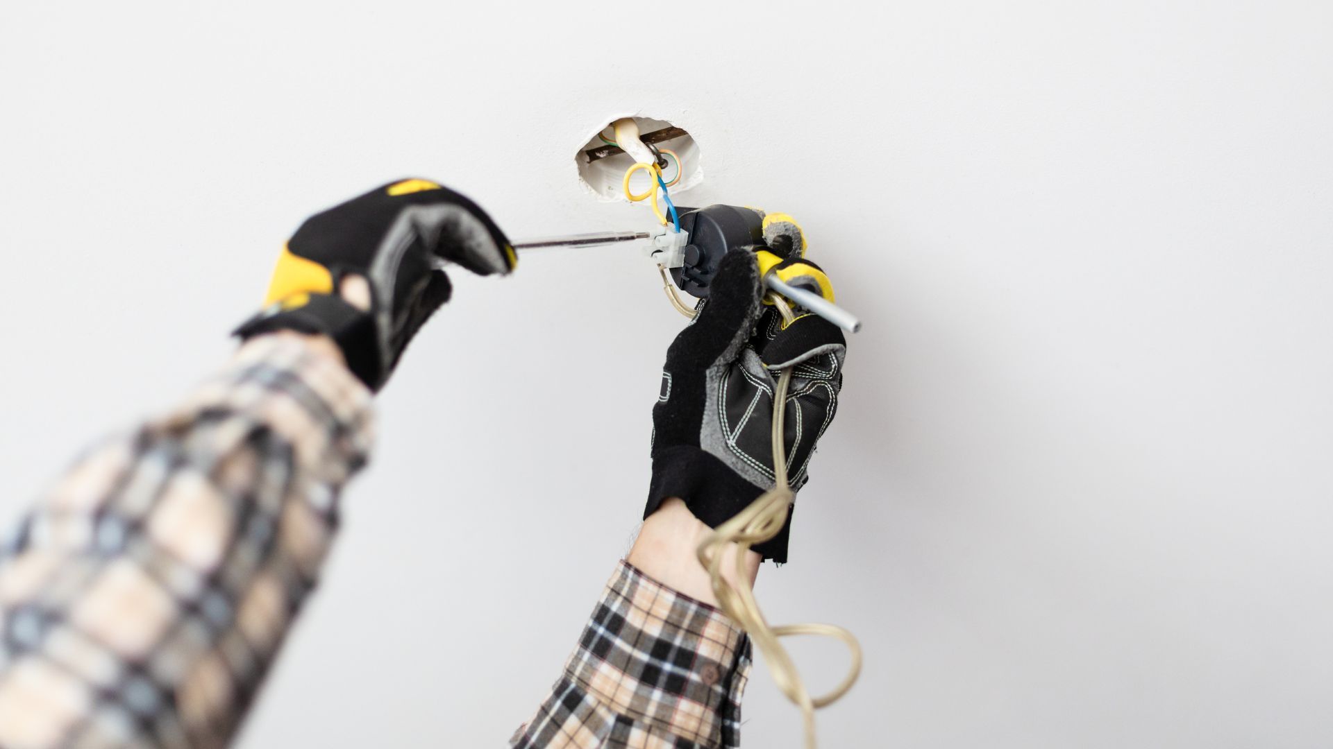 A person is installing a light fixture on a wall.