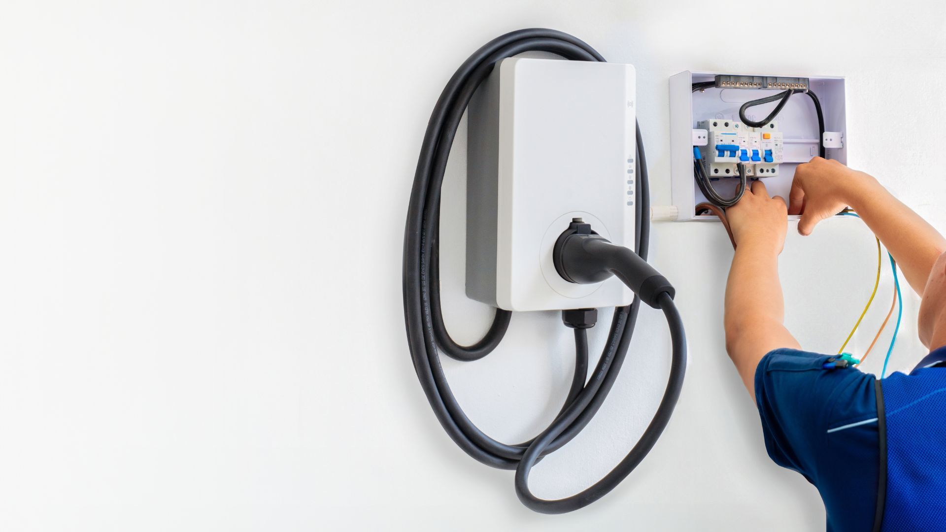 A person is installing an electric car charger on a wall.