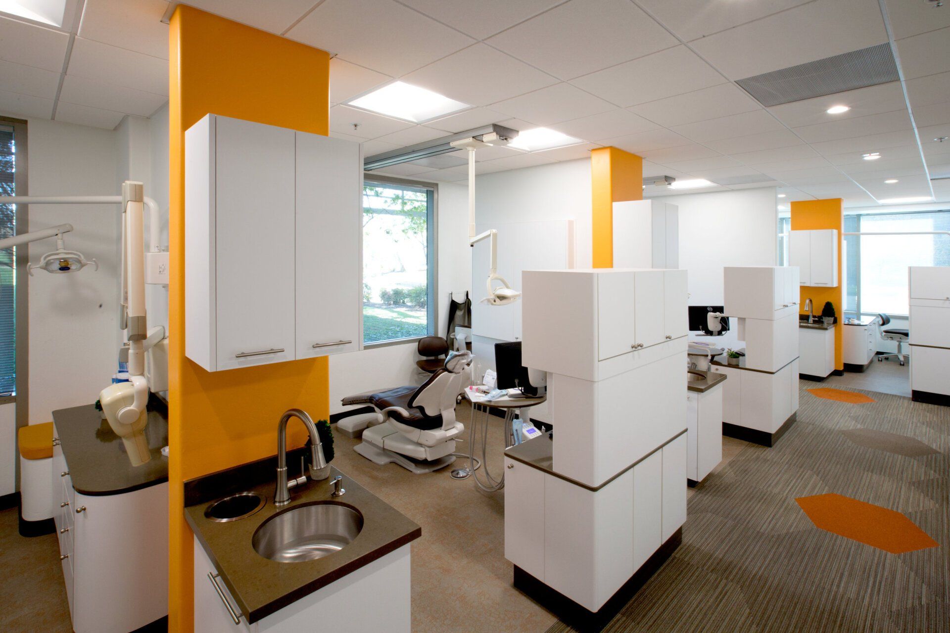 A dental office with a sink and chairs